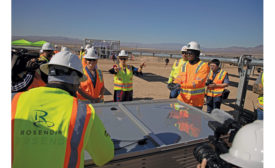 能源部长格兰霍姆在太阳能电池板旁与建筑工人交谈